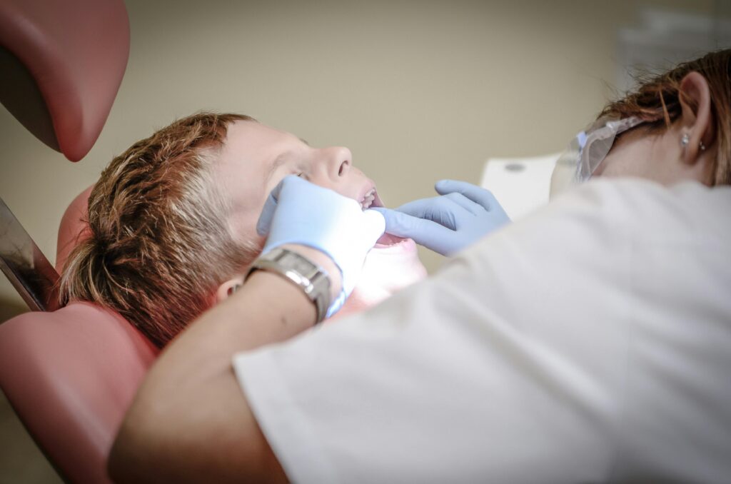 dentist-pain-borowac-cure-52527-52527 Dentist Woman Wearing White Gloves and White Scrubsuit Checking Boy's Teeth